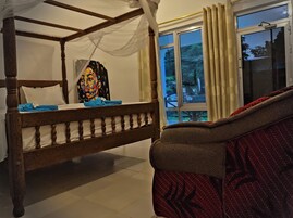 Una habitación con una cama con dosel, una ventana con cortinas y un sofá estampado.