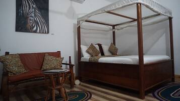 Una habitación con una cama con dosel, un sofá con cojines estampados, una pequeña mesa redonda y una alfombra colorida.