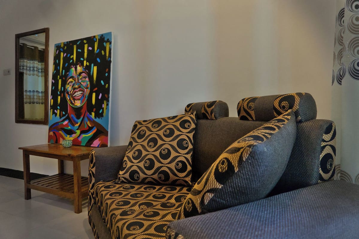 A living room with a patterned sofa, a small wooden table, and a colorful painting on the wall.