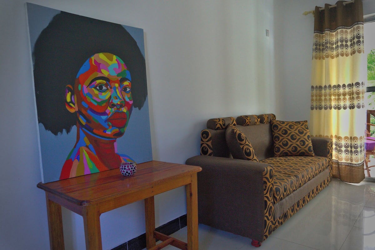 A living room with a colorful painting, a patterned sofa, and a small table.