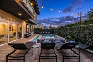 A modern outdoor pool area with lounge chairs and string lights.