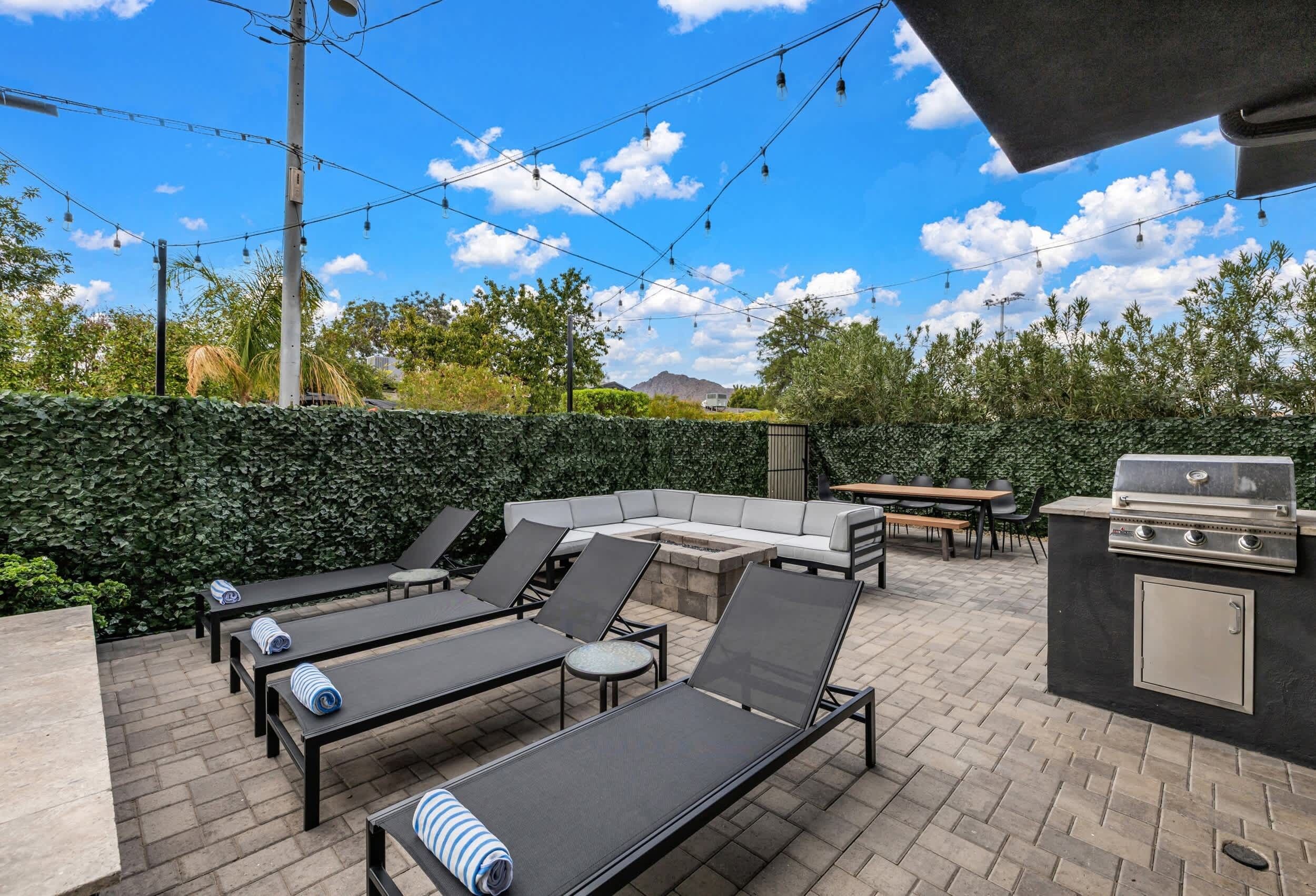 An outdoor patio with lounge chairs, a barbecue grill, and a dining area.
