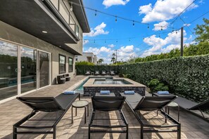 A modern outdoor pool area with lounge chairs and a stone wall.