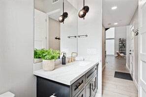 A modern bathroom with a large mirror, a white countertop, and a potted plant. - Lavish Luxuries-Pool/Spa, Games, Walk To Old Town! (Scottsdale)