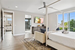 A modern bedroom with a large bed, a ceiling fan, and a view of the outdoors. - Lavish Luxuries-Pool/Spa, Games, Walk To Old Town! (Scottsdale)