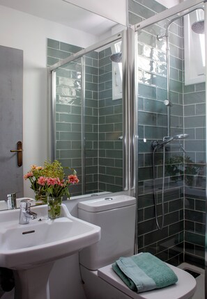 Une salle de bain avec une douche à parois de verre, un lavabo blanc et des toilettes.