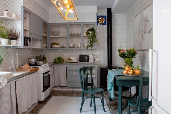 A compact kitchen with a microwave, stove, and a dining area with chairs.