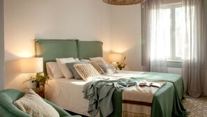 Une chambre bien rangée, avec un lit, des tables de chevet, une chaise et une fenêtre avec des rideaux.