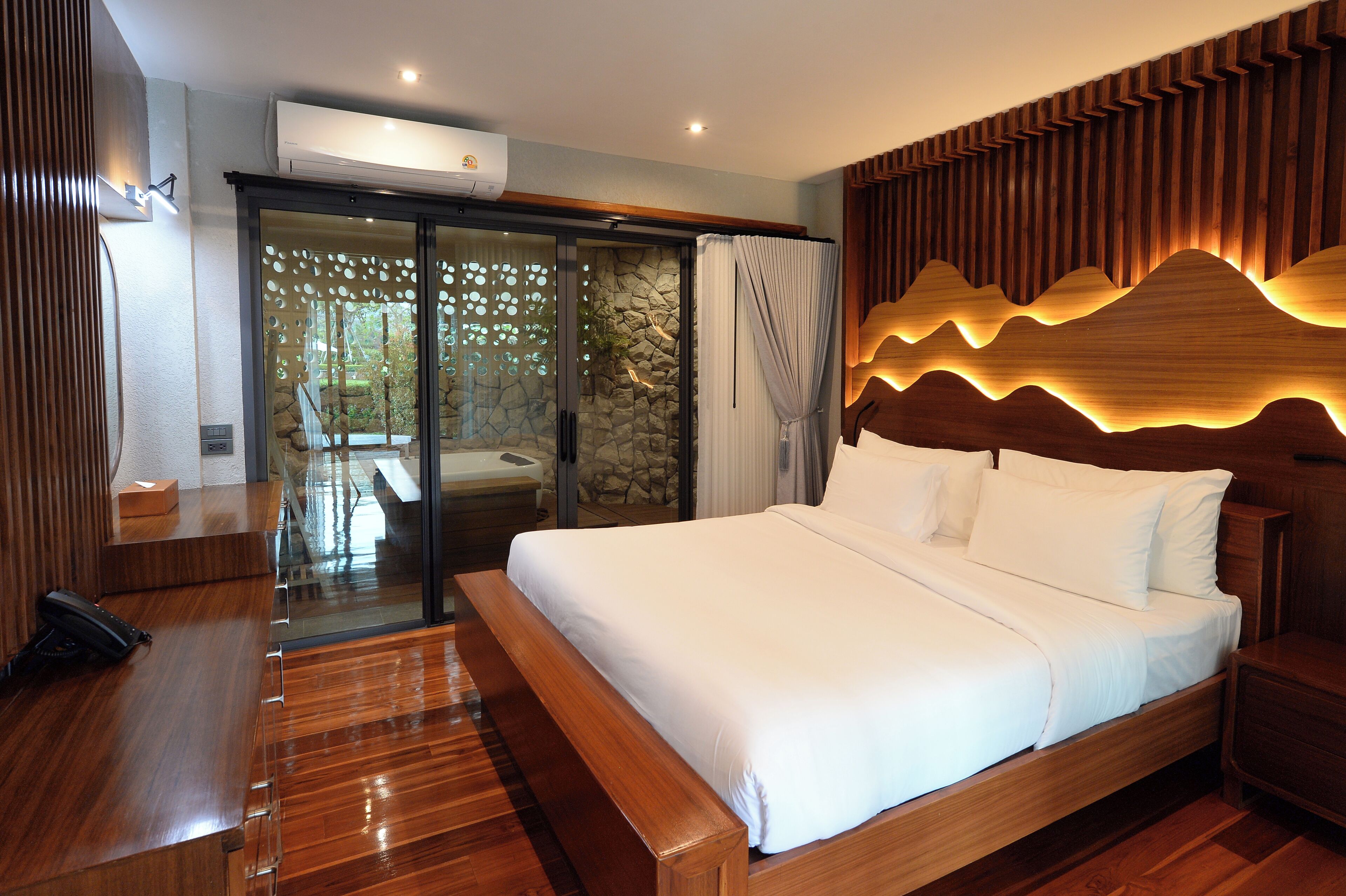 A bedroom with a large bed, wooden headboard, and a sliding glass door leading to a balcony.