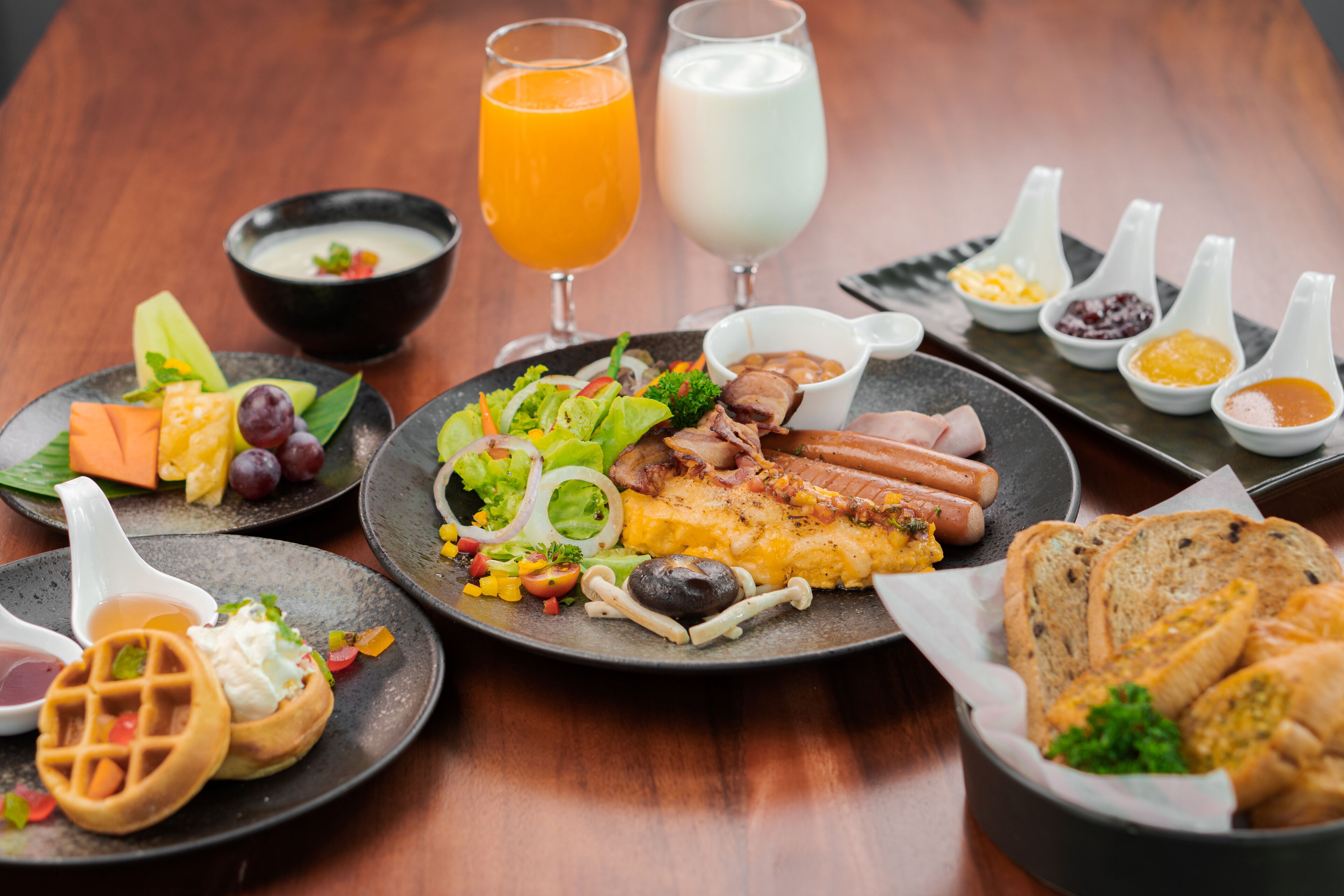 Una mesa de madera con una variedad de platillos, bebidas y condimentos para el desayuno.
