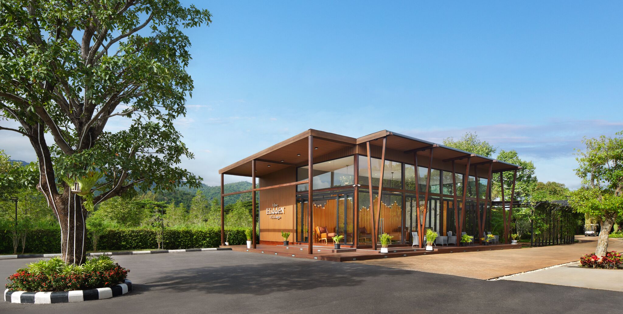 A modern glass building with a wooden exterior, labeled "The Hidden Village."