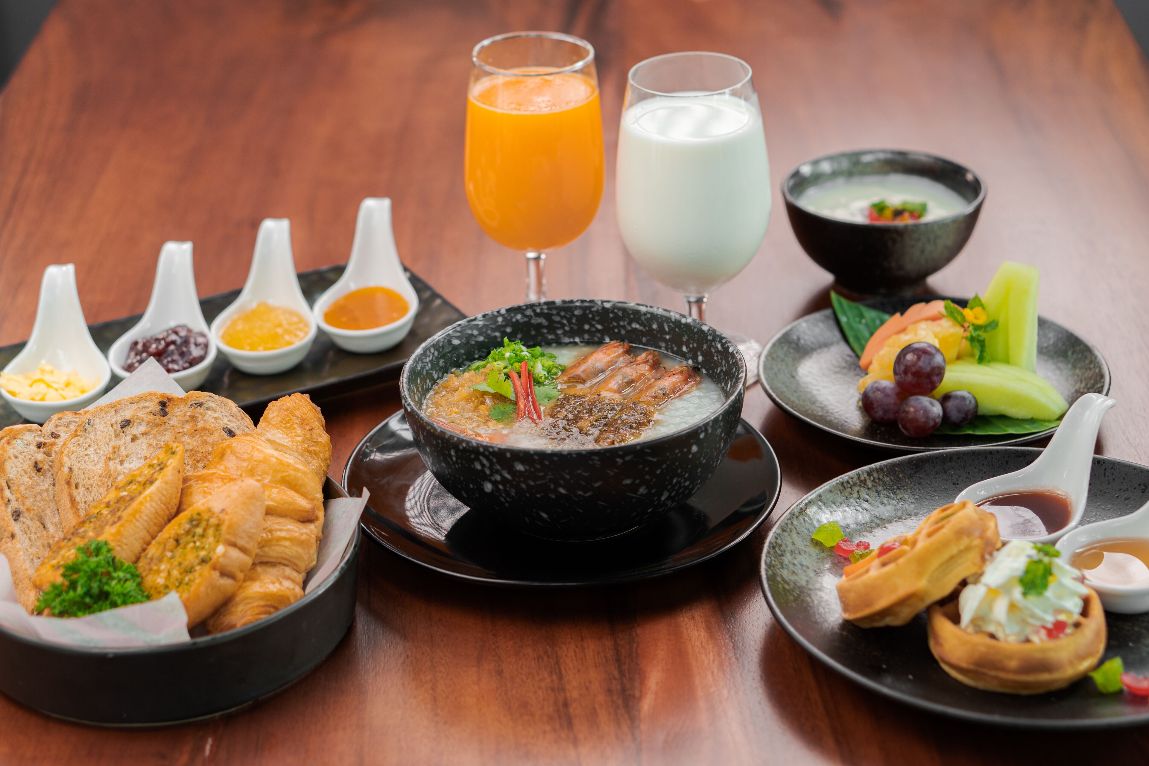 A variety of dishes including soup, bread, and fruit on a wooden table.