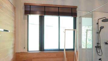 A bathroom with a wooden ceiling, a toilet, a shower, and a window.