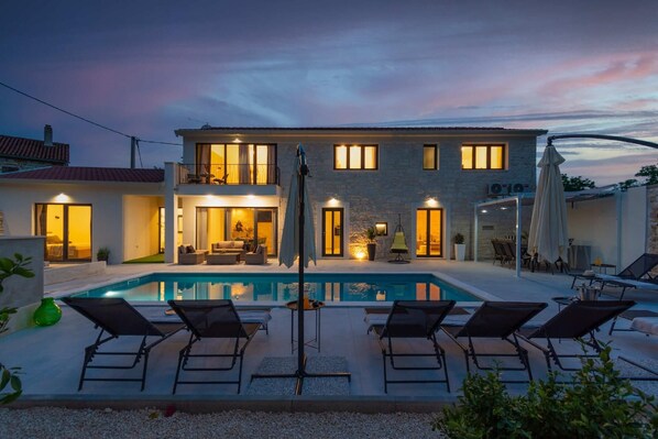 Relax by the pool in a tranquil setting, surrounded by comfortable lounge chairs and a shaded area.