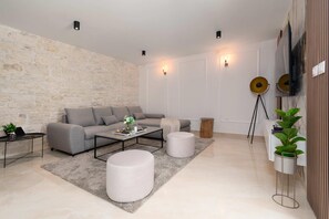Relax in this stylish living room with a grey sofa, round ottoman, and coffee table.