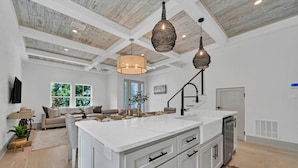 Cocina amplia con una isla grande, armarios blancos e iluminación colgante.