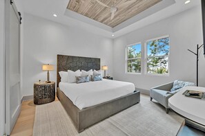 Um quarto moderno com uma cama grande, duas mesas de cabeceira, uma cadeira e uma escrivaninha.