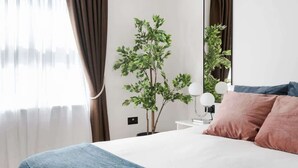 Une chambre à coucher bien rangée, avec un lit, une table de chevet dotée d’une lampe et un miroir.