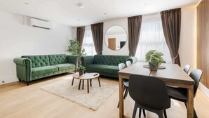 Un salon moderne avec un canapé vert, une table à manger en bois et un miroir rond.