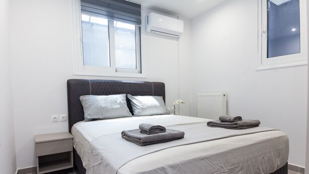 Une chambre à coucher moderne avec un lit, des tables de chevet et une fenêtre.