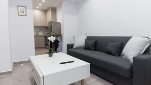 Un salon moderne avec un canapé gris, une table basse blanche et une télécommande posée dessus.