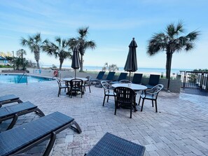 Un espace aménagé au bord de la piscine, avec des chaises longues, une table et des parasols.