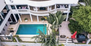 A multi-level building with a swimming pool, outdoor seating, and lush greenery. - La Villa des Fées (Douala)