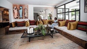 A spacious living room with a large sofa set, a coffee table with decorative items, and a large painting on the wall. - La Villa des Fées (Douala)