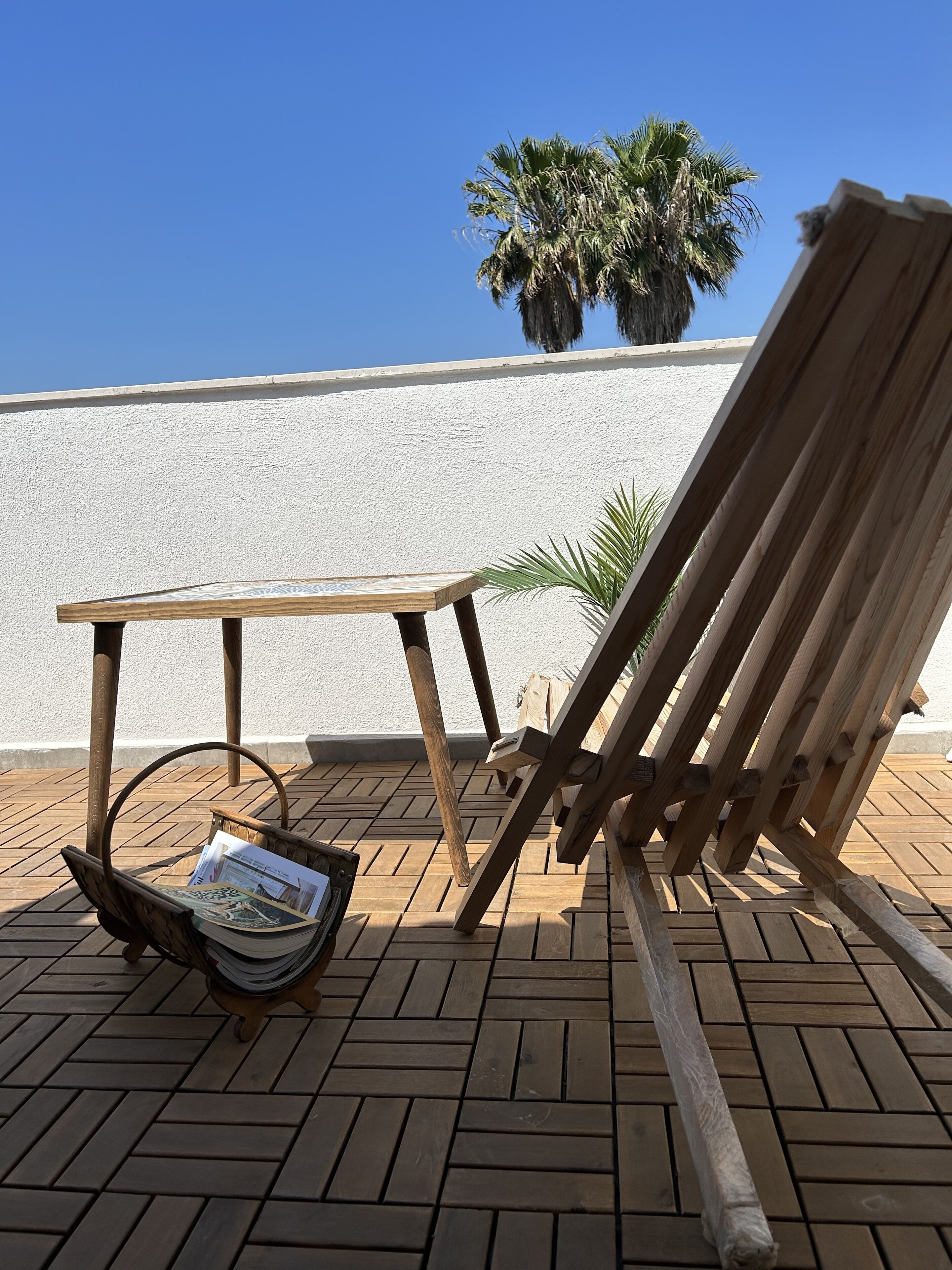 A wooden deck with a table and a lounge chair.