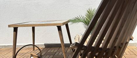 A wooden deck with a table and a lounge chair.
