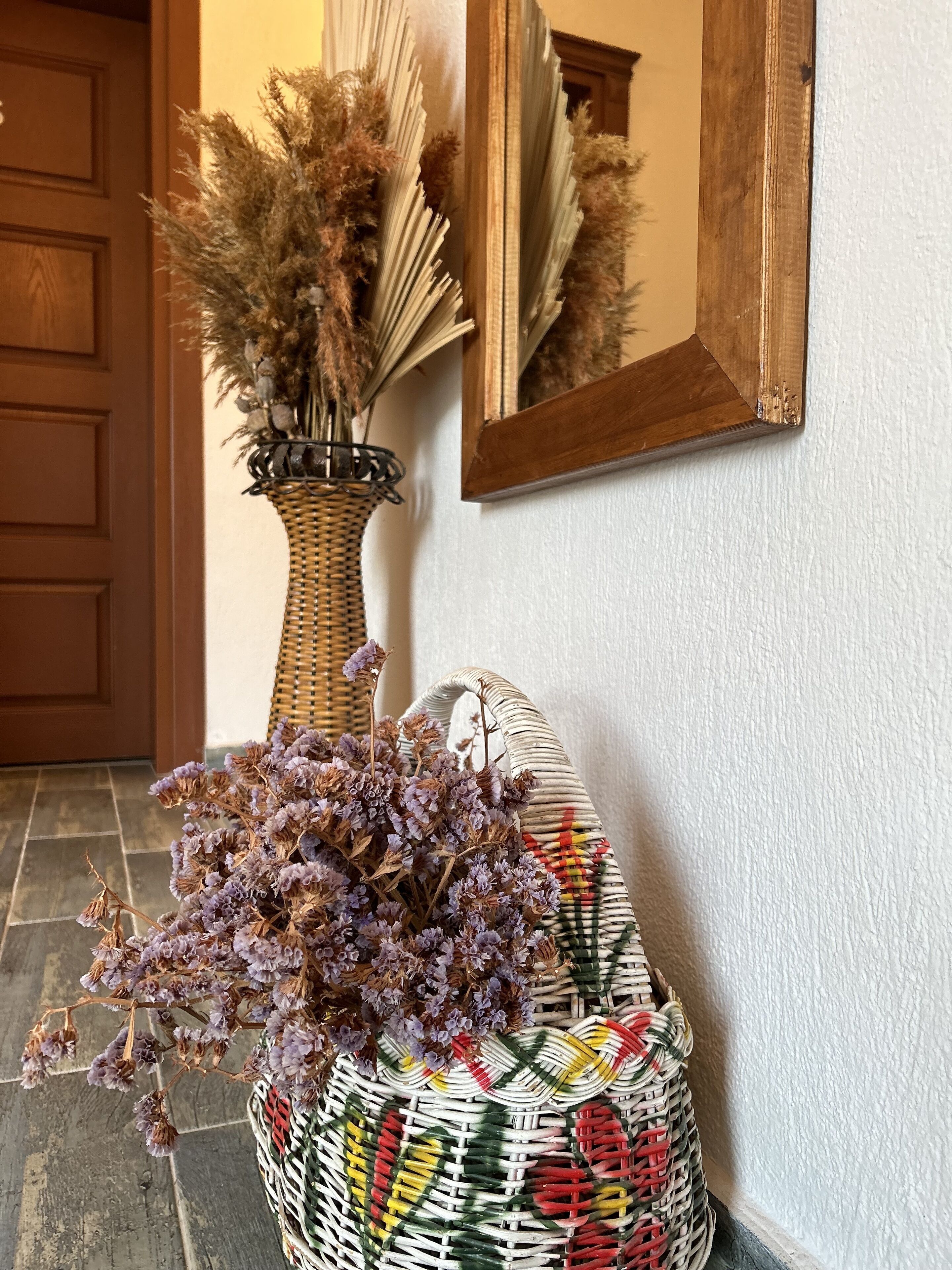 Ein Korbkörbchen mit getrockneten Blumen und eine geflochtene Tasche mit buntem Muster.