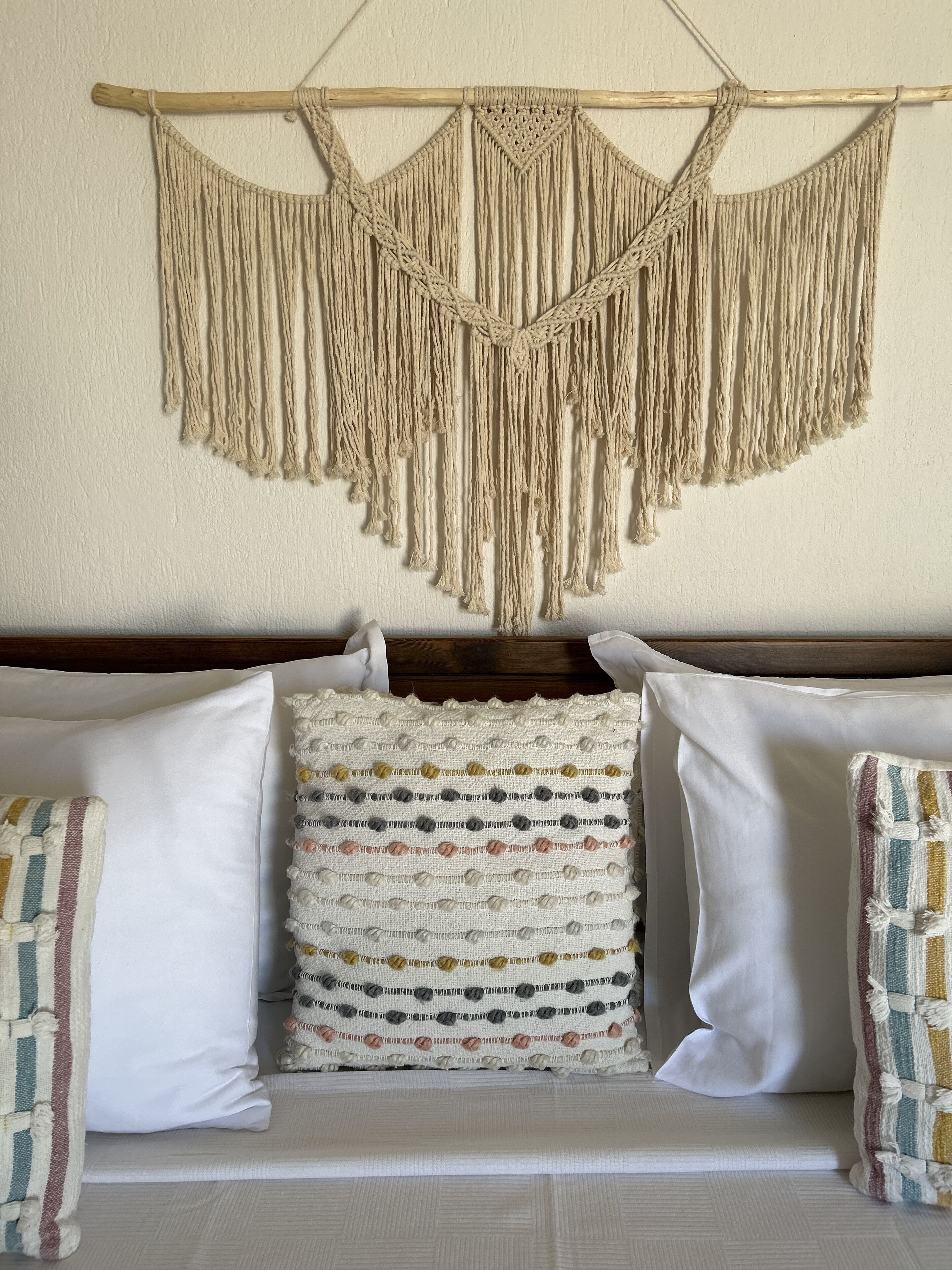 A bed with a macramé wall hanging above it.