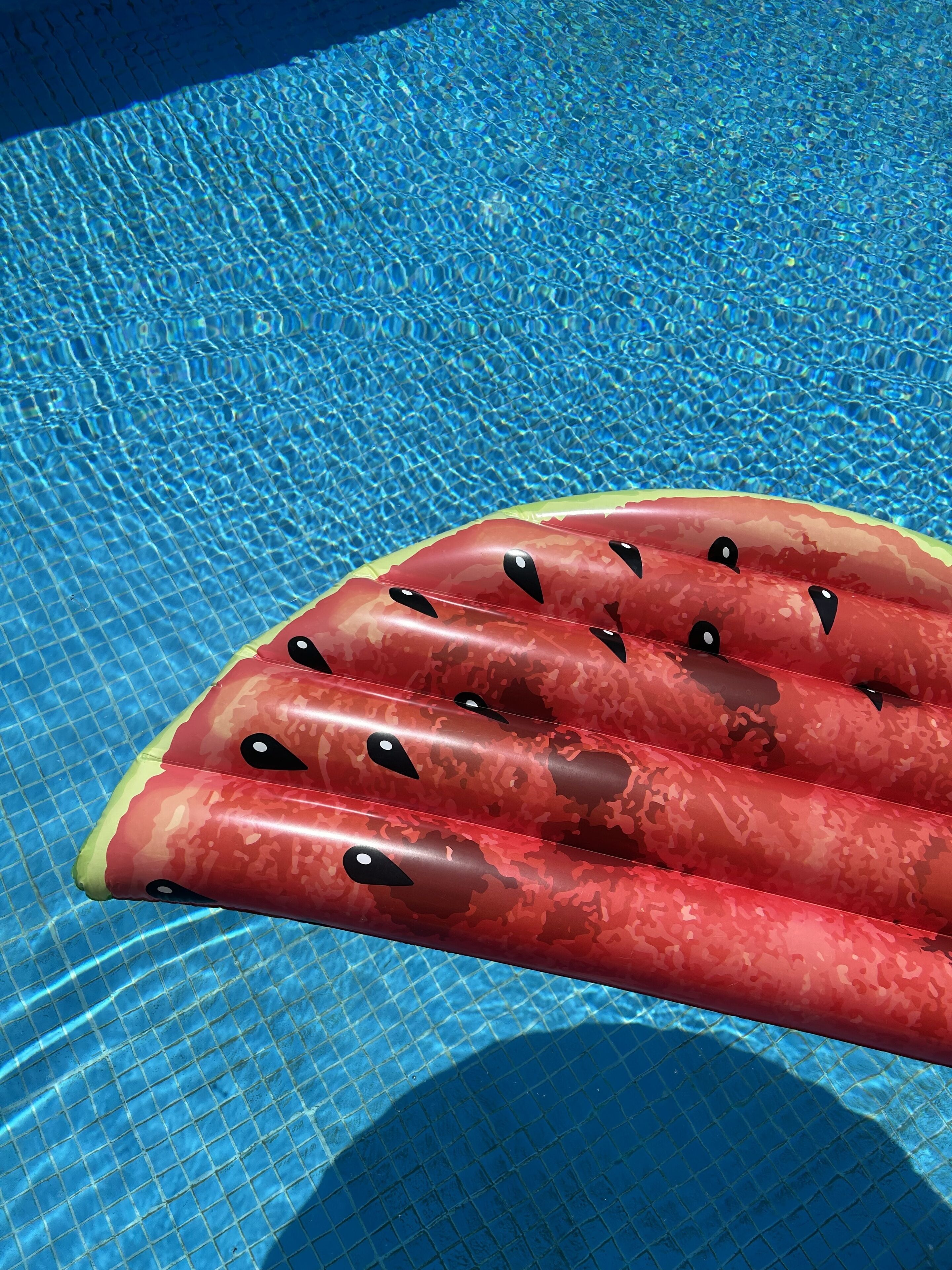 Una piscina con agua azul cristalina y un flotador inflable rojo con ojos negros.