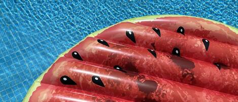 Una piscina con agua azul cristalina y un flotador inflable rojo con ojos negros.