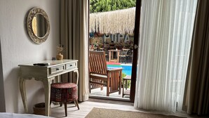 Una camera da letto con un letto, una scrivania, una sedia e vista su una zona con piscina.