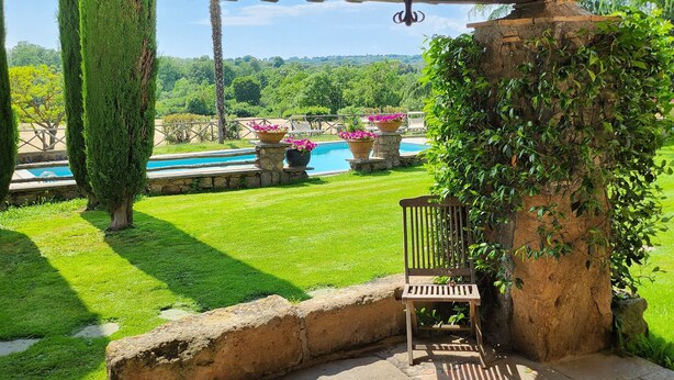 A covered patio with a wooden ceiling, a hanging lantern, a stone bench, and a view of a pool and garden. - 9 Bedroom Private vacation home in Lazio (Lazio)