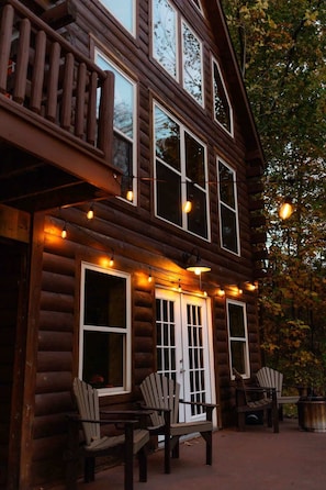 Une cabane en rondins dotée d’un balcon, de deux fenêtres et d’une porte avec des panneaux de verre.