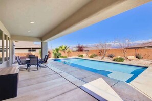 Une piscine avec un espace patio, du mobilier d’extérieur et une vue sur le paysage environnant.