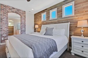 Une chambre avec une arche en briques, un mur en bois, un lit recouvert d’une couverture à motifs et deux lampes de chevet.