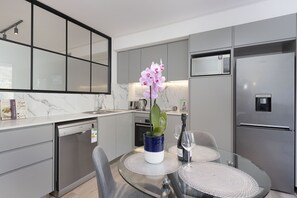 A modern kitchen with grey cabinets, a built-in microwave, and a stainless steel refrigerator.