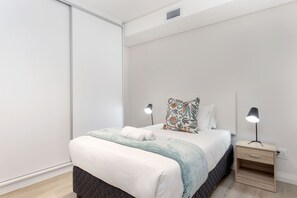 Un dormitorio moderno con cama, mesitas de noche y una mesilla.