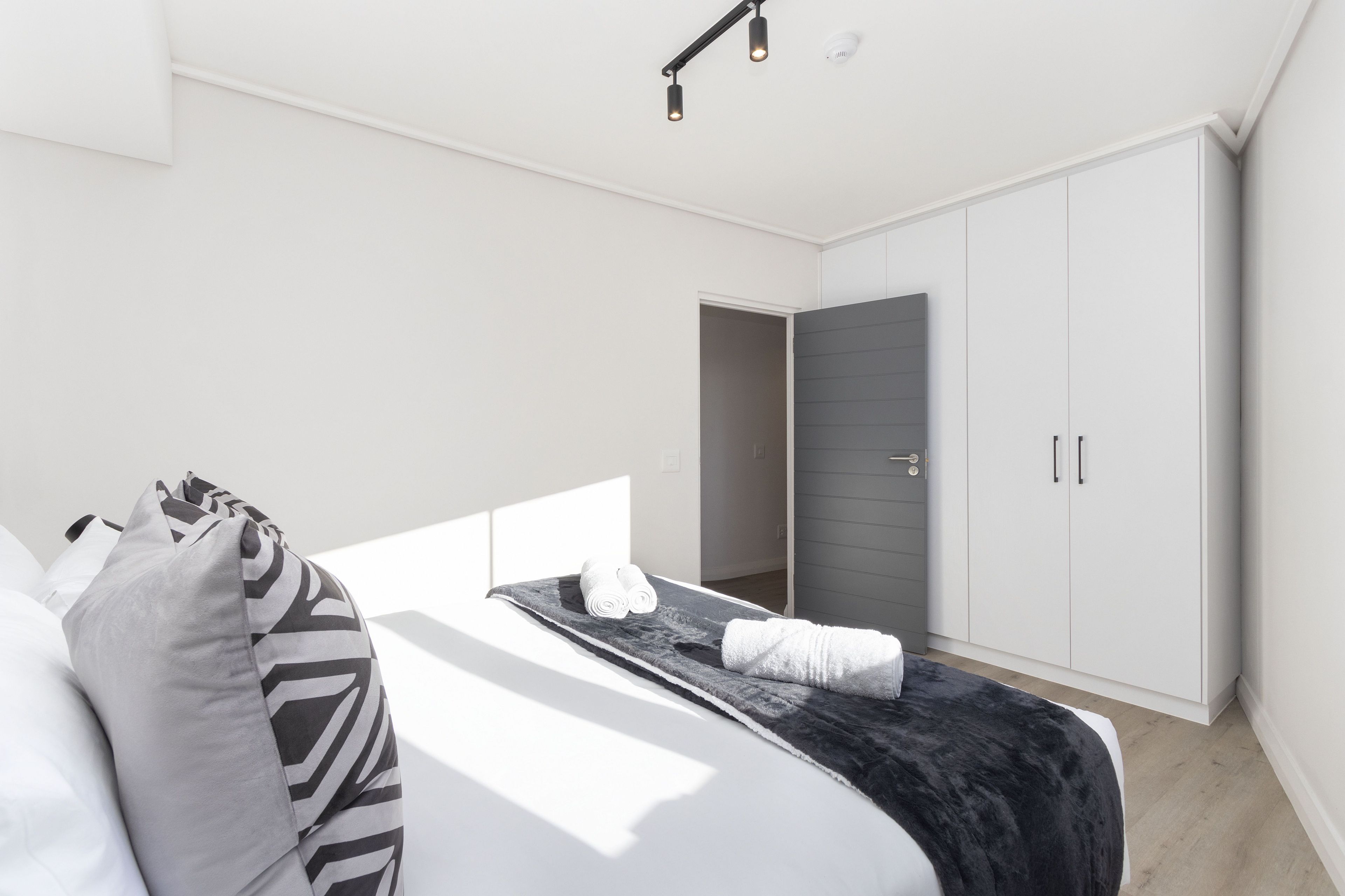 Een moderne slaapkamer met een bed, kussens, een dekbed en een kledingkast.