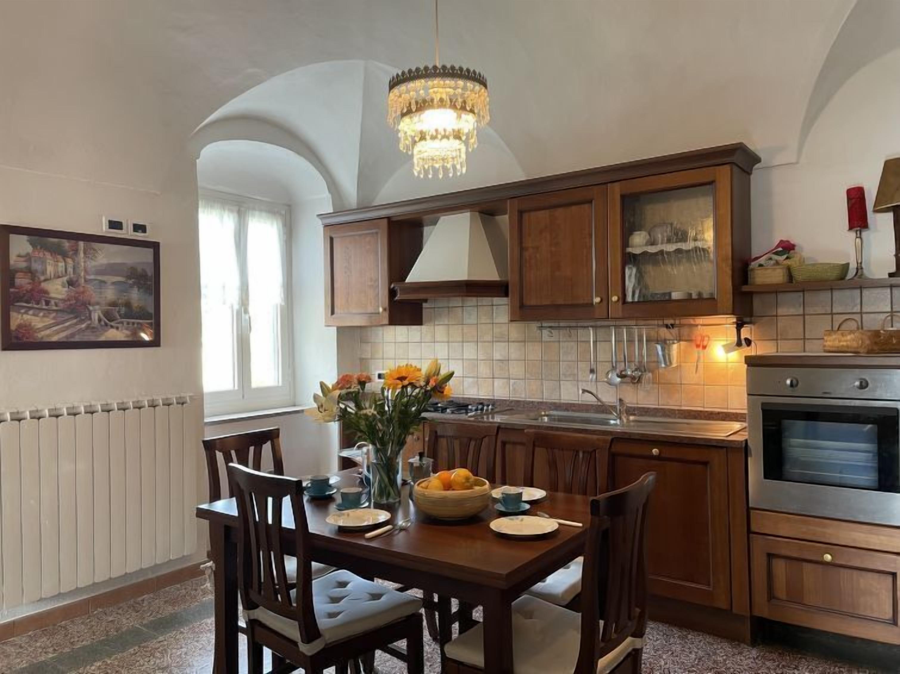Una cocina con armarios de madera, una araña y una mesa de comedor para cuatro.