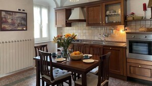 A kitchen with wooden cabinets, a chandelier, and a dining table set for four. - Casa Ferrando by Interhome (Torrazza)