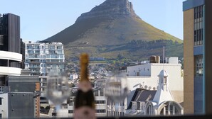 A cityscape with modern buildings and a prominent hill in the background. - The Tokyo 807 (Cape Town)