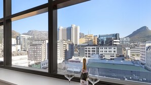 A bottle of wine and two glasses on a windowsill with a cityscape view. - The Tokyo 807 (Cape Town)