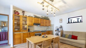 A modern kitchen with wooden cabinets, a dining table, and a sofa. - Isola di Madesimo Apartments by Interhome (Madesimo)