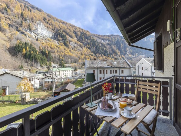 Un balcon avec une table préparée pour le petit-déjeuner, donnant sur un village de montagne.