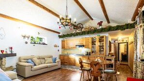 Un salon chaleureux avec un canapé, une table à manger et des chaises, un plancher en bois et une cuisine dotée de meubles en bois.