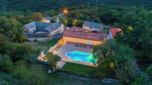 Vista aérea de una propiedad con piscina, varias edificaciones y vegetación circundante.